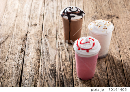 Strawberry, chocolate and white iced milkshakes on wooden table.Copy space Strawberry, chocolate and white iced milkshakes on wooden table.Copy space 70144406