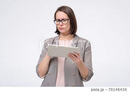 Puzzled caucasian lady hold tablet in hands trying to book tickets in internet online Puzzled caucasian lady hold tablet in hands trying to book tickets in internet online 70146430