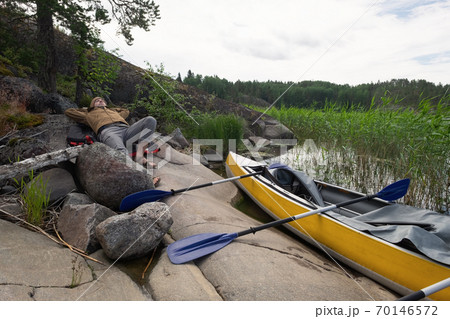 Man resting on the riverside after active paddling on kayak. Man resting on the riverside after active paddling on kayak. 70146572