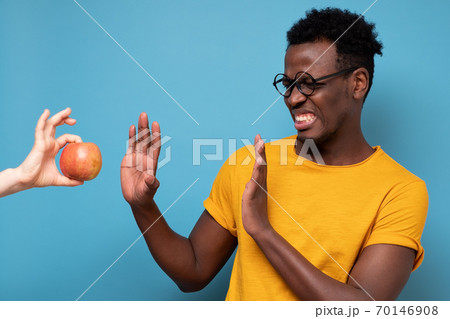 African young man rejecting apple isolated on blue background 70146908
