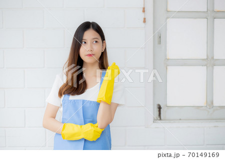 Portrait young asian woman is housekeeper in rubber gloves and apron for protection at home. 70149169