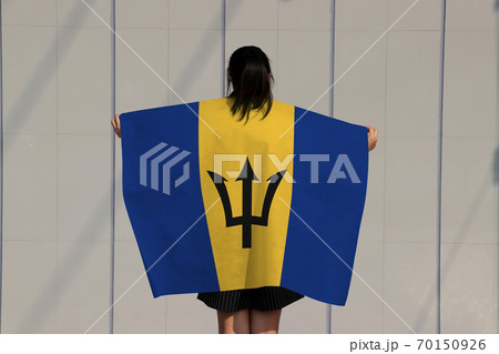 Woman holding Barbados flag on her shoulder and turn back on grey background. Woman holding Barbados flag on her shoulder and turn back on grey background. 70150926