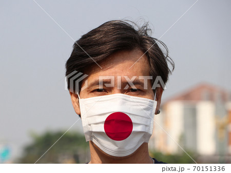 Japan flag on hygienic mask. Masked Asian man prevent germs. Japan flag on hygienic mask. Masked Asian man prevent germs. 70151336