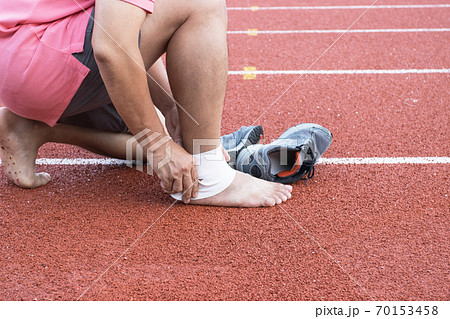 man applying compression bandage onto ankle injury After exercise concept Sports injuries. 70153458