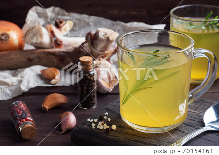 Homemade beef bone and vegetable broth with turmeric seasoning in a glass. Healthy food with collagen and amino acids. Copy space. Homemade beef bone and vegetable broth with turmeric seasoning in a glass. Healthy food with collagen and amino acids. Copy space. 70154161