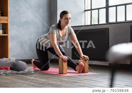 woman doing stretching exercise using props, block, Ardha Hanumanasana woman doing stretching exercise using props, block, Ardha Hanumanasana 70156636