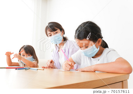 マスクを付けて勉強をする子供と塾講師 70157611