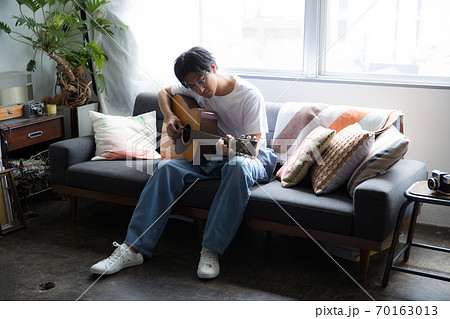 部屋でギターを弾くかっこいい男性の写真素材