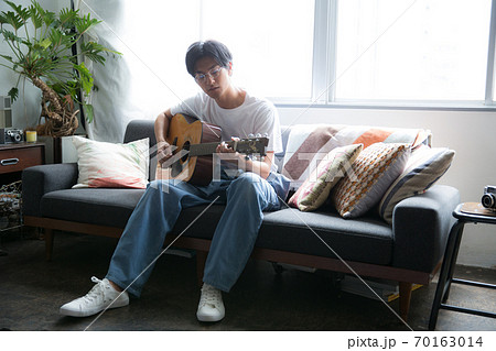 部屋でギターを弾くかっこいい男性の写真素材