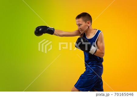 Teenage boxer against gradient neon studio background in motion of kicking, boxing 70165046