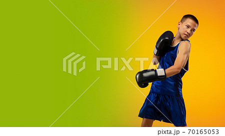 Teenage boxer against gradient neon studio background in motion of kicking, boxing 70165053