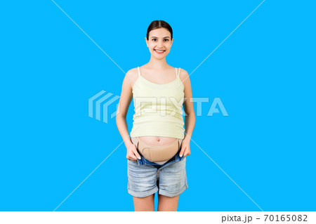 Portrait of pregnant woman wearing pregnancy bandage at blue background with copy space. Orthopedic abdominal support belt concept Portrait of pregnant woman wearing pregnancy bandage at blue background with copy space. Orthopedic abdominal support belt concept 70165082