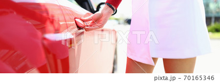 Woman stands next to red car hand on doorknob. Woman stands next to red car hand on doorknob. 70165346
