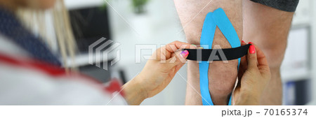 Fixation of kinesio tape on the patient's leg. 70165374