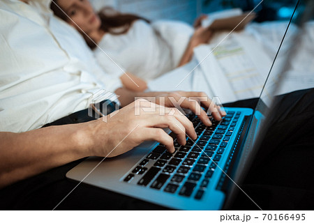 Young businessman is typing on laptop in bedroom.  70166495