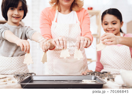 Grandmother with grandchildren shows cookie. 70166845