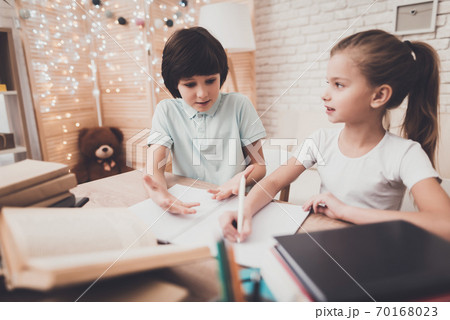 Brother helps sister do homework at table.  70168023