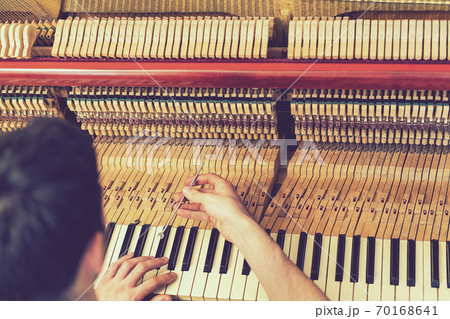 Piano tuning process. closeup of hand and tools of tuner working on grand piano. Detailed view of Upright Piano during a tuning. toned Piano tuning process. closeup of hand and tools of tuner working on grand piano. Detailed view of Upright Piano during a tuning. toned 70168641
