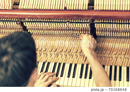 Piano tuning process. closeup of hand and tools of tuner working on grand piano. Detailed view of Upright Piano during a tuning. toned 70168648