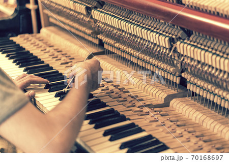 Piano tuning process. closeup of hand and tools of tuner working on grand piano. Detailed view of Upright Piano during a tuning. toned 70168697