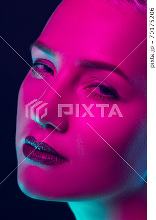 Portrait of female fashion model in neon light on dark studio background. 70175206