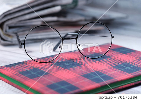 eyeglass, notepad and newspaper on table . 70175384