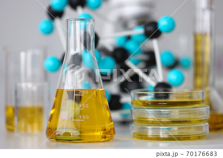 Glass test tubes with yellow viscous liquid stand on table in chemical laboratory closeup Glass test tubes with yellow viscous liquid stand on table in chemical laboratory closeup 70176683