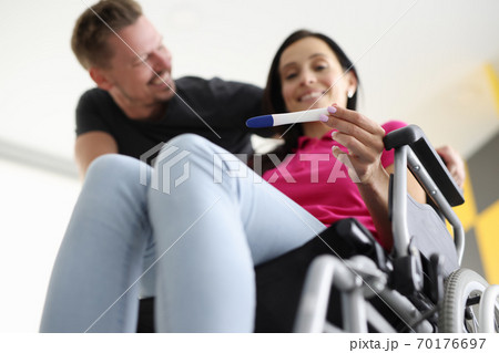 Disabled woman in wheelchair is holding test with her husband at home. Disabled woman in wheelchair is holding test with her husband at home. 70176697