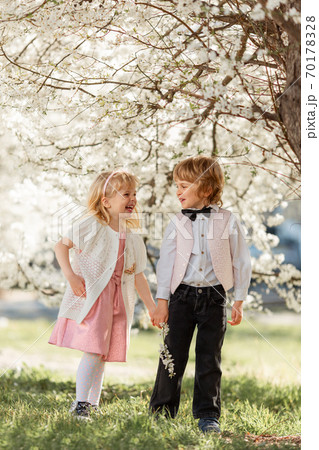 Happy sister and brother are playing in blossom cherry garden outdoors. Happy sister and brother are playing in blossom cherry garden outdoors. 70178328