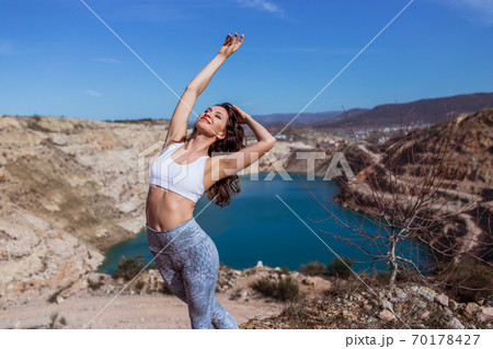 Young pretty woman is practicing yoga at mountain lake 70178427