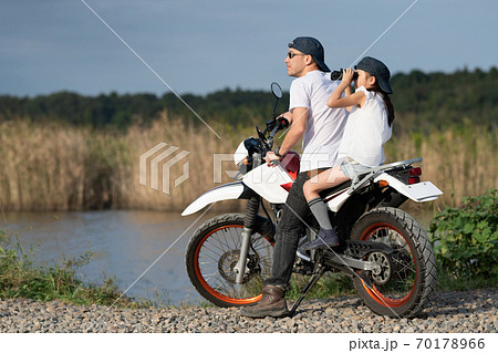 オフロードバイクに2人乗りをする父と娘の写真素材