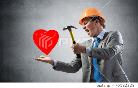 Furious businessman going to crash red heart Furious businessman going to crash red heart 70182228