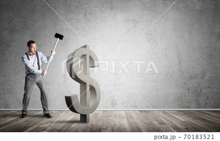 Determined banker man in empty concrete room breaking dollar figure Determined banker man in empty concrete room breaking dollar figure 70183521