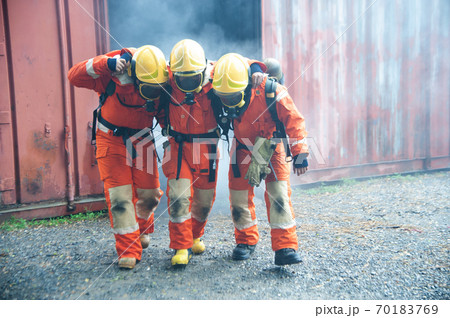Firefighters are helping workers by pulling out of the burning building. 70183769