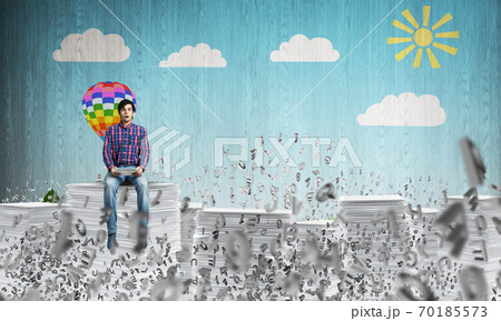 Young man sitting on pile of paper documents. 70185573