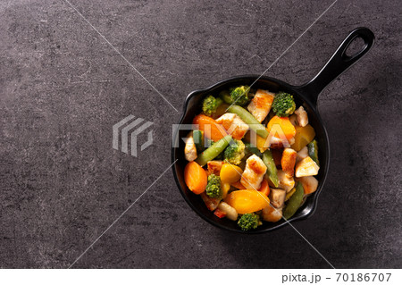 Stir fry chicken with vegetables on iron pan on black background. Stir fry chicken with vegetables on iron pan on black background. 70186707