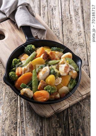 Stir fry chicken with vegetables on iron pan on wooden table	 70186717