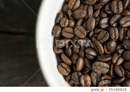 Bowl filled of fresh arabica or robusta coffee beans on a wooden table. Bowl filled of fresh arabica or robusta coffee beans on a wooden table. 70186820