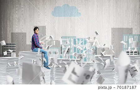 Young man sitting on pile of paper documents. Young man sitting on pile of paper documents. 70187187