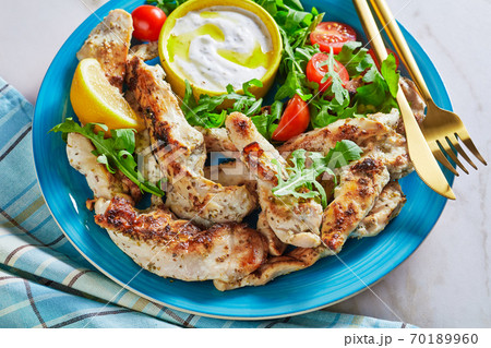 Grilled chicken with arugula salad on a blue plate 70189960