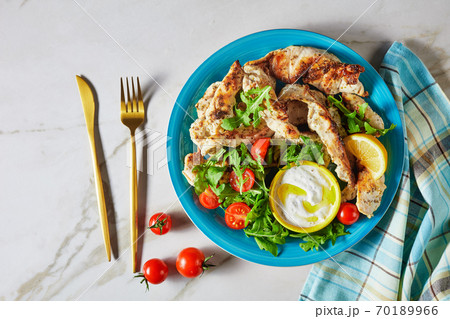 Grilled chicken with arugula salad on a blue plate 70189966