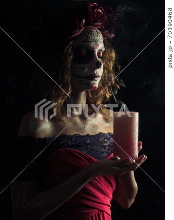 Santa muerte makeup young woman holding burning candle 70190468