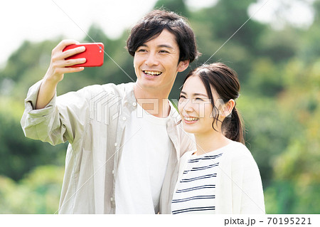 屋外でセルフィを撮る若い男女の写真素材