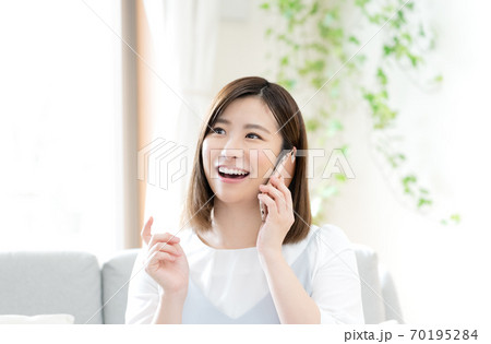 スマホで通話する女性【リビング】 スマホで通話する女性【リビング】 70195284