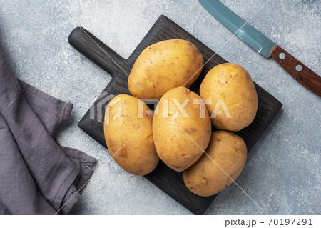 Several tubers of raw potatoes on a grey concrete background. Copy space. 70197291