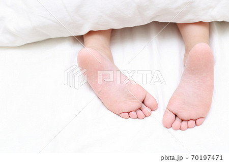 ベッドで眠る女の子の素足 70197471