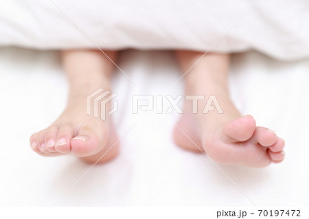 ベッドで眠る女の子の素足 70197472