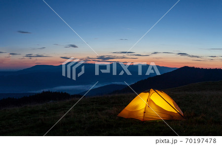 Orange luminous tent on the mountain in evening or early morning 70197478