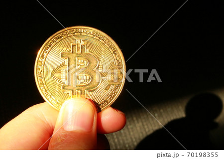 黄金に光り輝くビットコインの仮想通貨と手 の写真素材