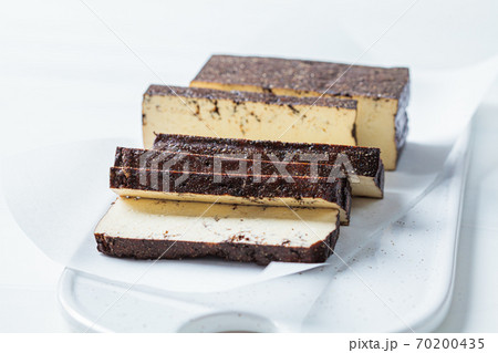 Sliced smoked tofu on white board, white background. Vegan food concept. 70200435